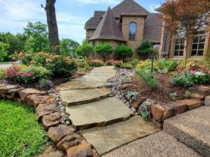 a front yard designed with stone pathways and flower beds